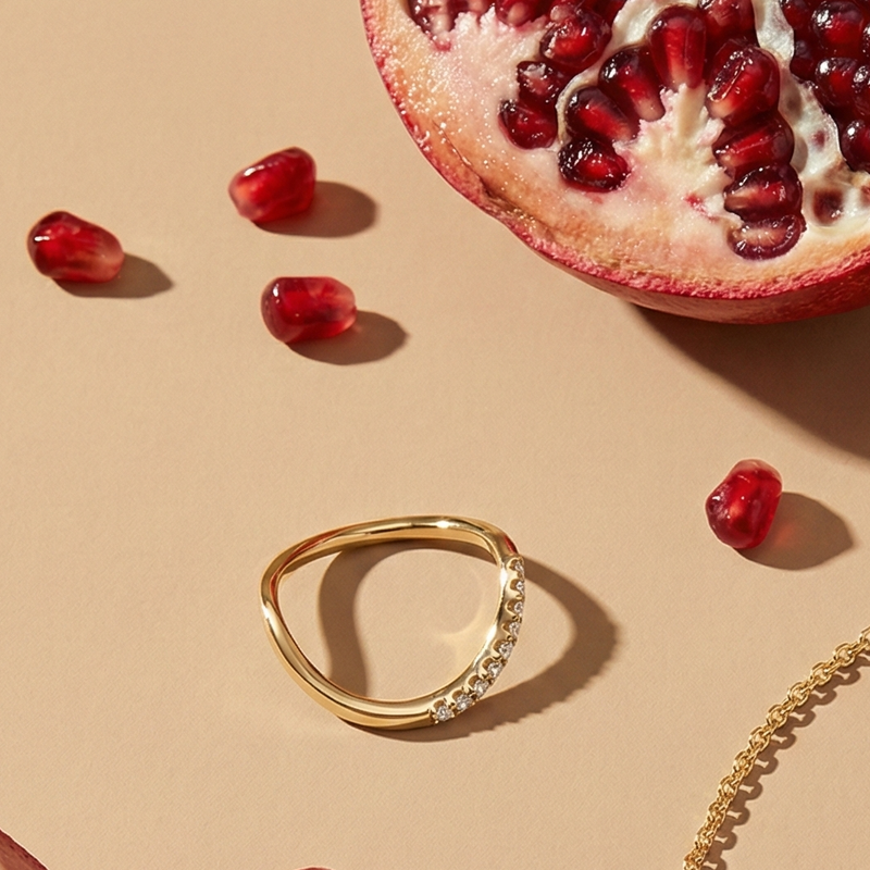 Gold ring with pomegranate on a beige background